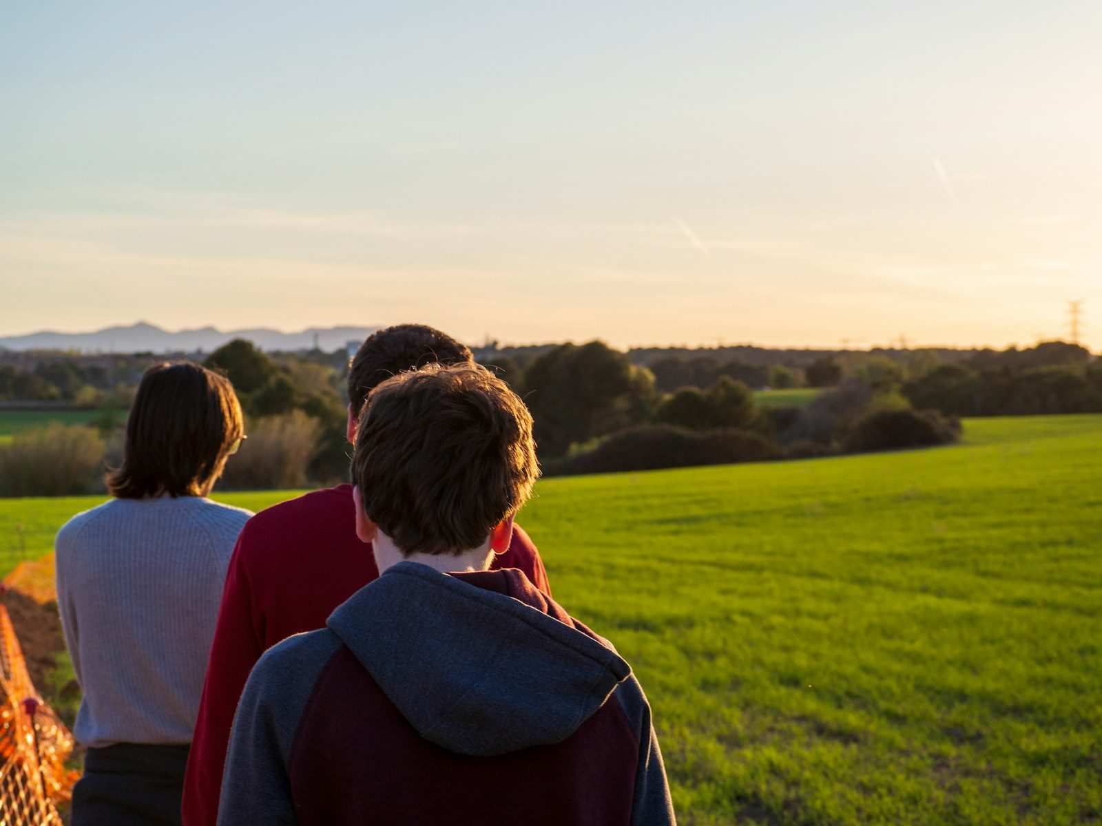 A family looking out over open country at sunset, seen from behind